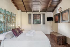 a bedroom with a large white bed and a television at El Puente Ronda in Ronda