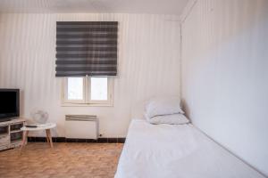 a bedroom with a bed and a tv and a window at Chez Lina - studio avec terrasse in Le Lavandou