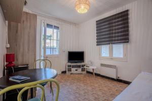 a living room with a table and a television at Chez Lina - studio avec terrasse in Le Lavandou