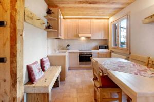 a kitchen with wooden cabinets and a table and a dining room at Casa Clus Bormio apartments 1 in Valdisotto