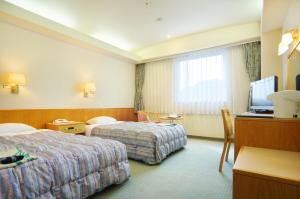 a hotel room with two beds and a television at New Royal Hotel Shimanto in Shimanto