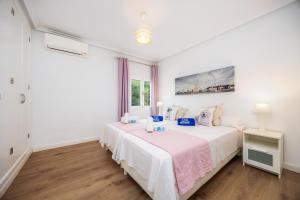 a white bedroom with a bed and a window at La Casita in Pollença