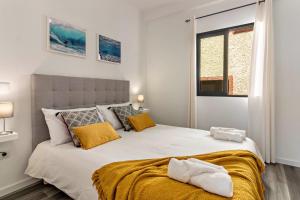 a bedroom with a large white bed with yellow pillows at Casa Homem do Mar in Paul do Mar