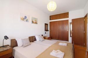 a bedroom with two beds and a wooden cabinet at Cabanas Mar 94 in Cabanas de Tavira