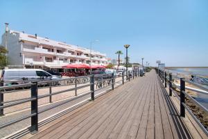 a wooden boardwalk on the beach with a building at Cabanas Mar 94 in Cabanas de Tavira