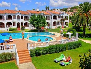 a resort with a swimming pool and people in a yard at Girasol Garden Superior 2-b in Menorca