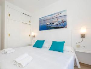 a white bedroom with a large bed with blue pillows at Girasol Garden Superior 2-b in Menorca +19 photos