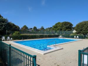 a swimming pool with chairs and a fence around it at Ty Dacoli - piscine et plage in Le Pouliguen
