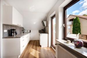 a kitchen with white cabinets and a large window at Ferienwohnung In Bempflingen in Bempflingen