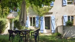 a table with chairs and an umbrella in front of a house at Le Gite Des Peyreyres in Lespéron