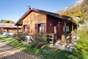 a small wooden cabin with flowers in the grass at Casa Bucaneve in Barzio