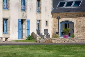 a building with blue doors and chairs in the grass at Maison Indépendante Sur Jardin in Mahalon