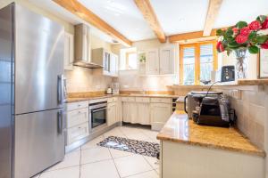 a kitchen with white cabinets and a stainless steel refrigerator at Maison Indépendante Sur Jardin in Mahalon