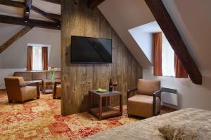 a room with a tv and a couch and chairs at Hotel Singer in Ludvíkov