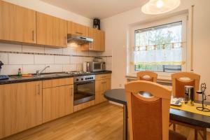 a kitchen with wooden cabinets and a table and a counter at Ferienwohnung Steinhilber 2 in Eriskirch