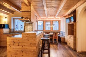 a kitchen with wooden cabinets and a bar with stools at Chalet Osmar Appartamento 2 in Campitello di Fassa
