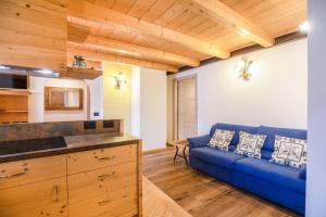 a living room with a blue couch and wooden ceilings at Chalet Osmar Appartamento 2 in Campitello di Fassa