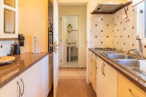 a kitchen with white cabinets and a sink at Villa Echium T2 in Caniço +21 photos