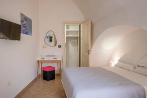 a bedroom with a white bed and a television at Dimora Egilò - Violet in Nardò