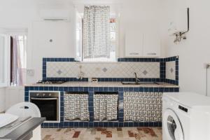 a kitchen with blue and white tiles and a washer at Sea Nest in Balestrate +28 photos
