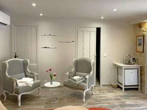a living room with two chairs and a table at La Colombière in Salviac +11 photos