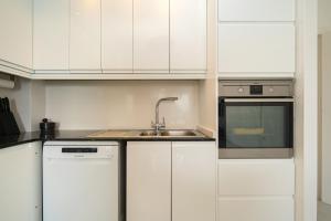 a kitchen with white cabinets and a sink at Costabella Altea in Altea