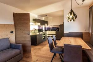 a kitchen and dining room with a wooden table and chairs at Kieserhof Apartment Berg in Terento