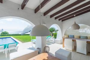 a living room with a table and a swimming pool at Villa Bini Andu in Binibeca