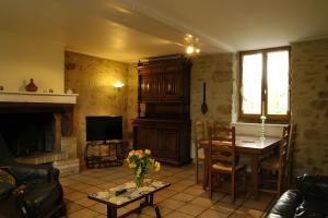a living room with a fireplace and a table and a television at Haras de la fontaine Diva in Poligny