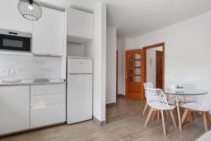 a kitchen with white appliances and a table and chairs at Apartamento Puerto Playa in Puerto del Rosario +13 photos