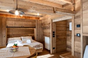 a bedroom in a log cabin with a bed and a table at Alpine Mood Apartments in Falcade