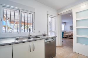 a kitchen with a sink and a living room at Precioso chalet a pie de playa in Punta Umbría
