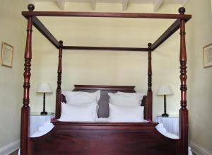 a wooden canopy bed with white pillows on it at De Kothuize 16 in Graaff-Reinet