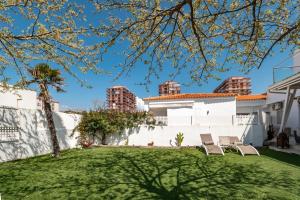 a yard with two chairs and a white house at Precioso chalet a pie de playa in Punta Umbría