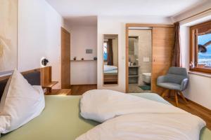 a bedroom with a bed and a chair and a mirror at Pixnerhof - Ferienwohnung Gala in Kastelbell-Tschars