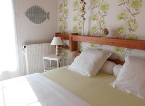 a bedroom with a bed with white sheets and flowers on the wall at Maison d'Hôtes - La Marée Hôtes in Piriac-sur-Mer