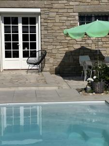a patio with a chair and an umbrella and a pool at Maison d'Hôtes - La Marée Hôtes in Piriac-sur-Mer