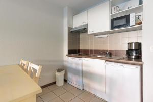a kitchen with white cabinets and a table at Appartement - Terrasses De L'Océan in Moliets-et-Maa