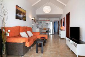 a living room with an orange couch and a kitchen at Punta Marea in Punta Mujeres