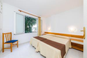 a bedroom with a bed and a chair and a window at Apartament Massanet bc in Canyamel