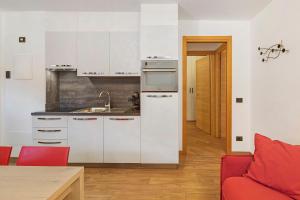 a kitchen with white cabinets and a red couch at Appartamenti Via Dell'Asilo in Valdidentro