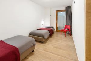 a hotel room with two beds and a red chair at Appartamenti Via Dell'Asilo in Valdidentro
