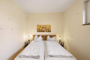 a bedroom with a bed with white sheets and pillows at Panoramablick über den Oberharz in Braunlage +26 photos