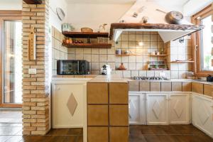 a kitchen with white cabinets and a brick wall at Nuràya in Sarroch +22 photos
