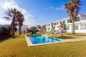 a swimming pool in front of a building with palm trees at Apartamento Cala en Forcat 34 in Cala en Blanes