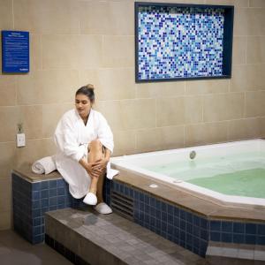 a woman sitting on a bench next to a tub at Hotel Habitel Prime in Bogotá