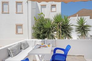 a white table and chairs on a balcony with palm trees at Pico Bello Patmos 14 in Patmos