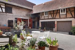 a patio with white chairs and potted plants in front of a building at Ferienwohnung im alten Vierseithof in Friedewald