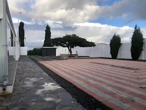 a brick walkway with a tree and a white fence at Los Cipreses in Ingenio