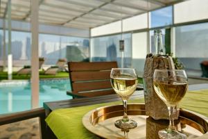 two glasses of white wine on a table near a pool at Los Cipreses in Ingenio